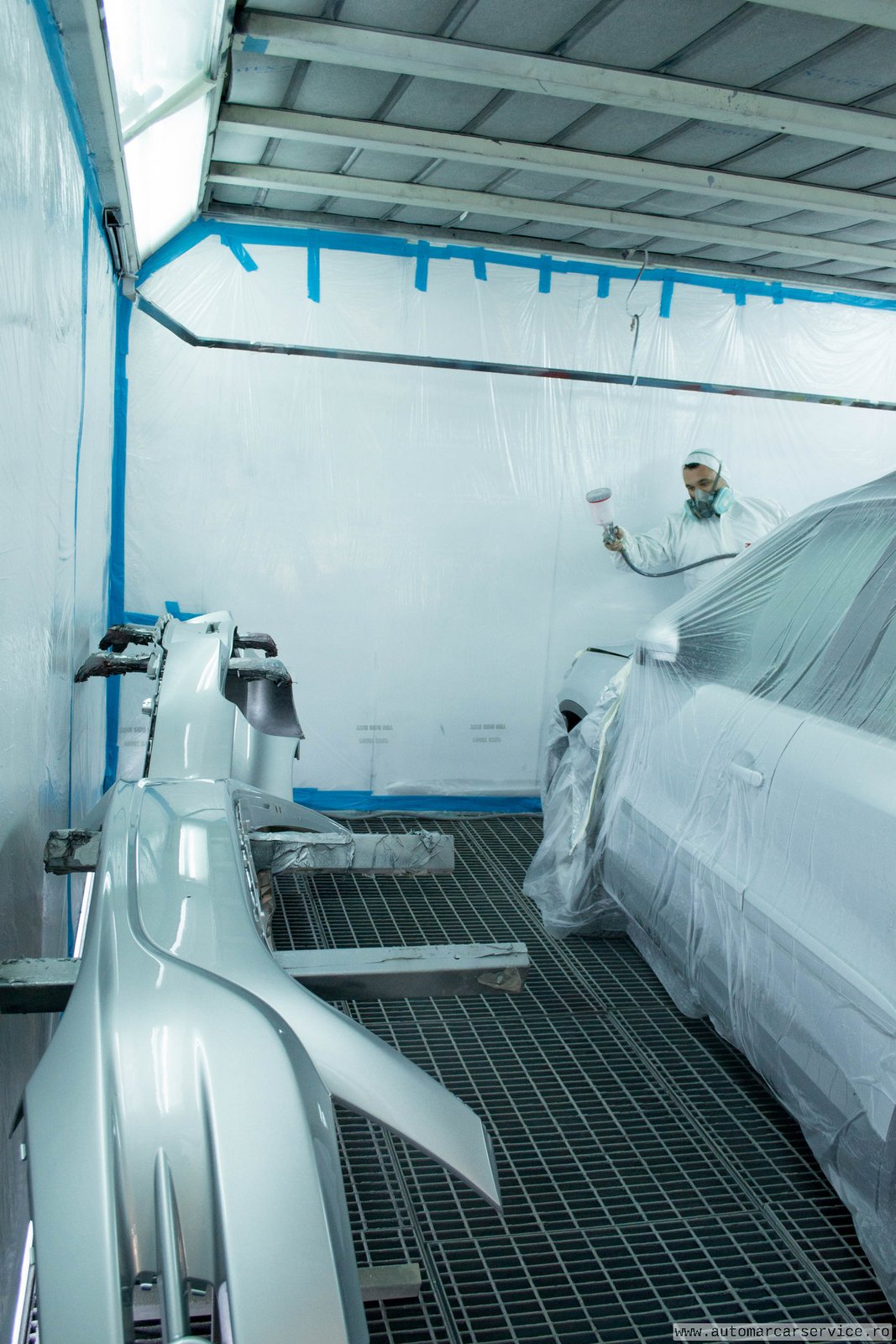 Vopsitor în cabina de vopsit, cu echipament de protecție